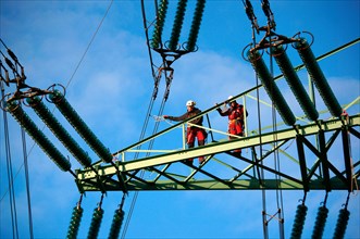 Industrial climbers on a transmission tower during maintenance