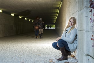 Young woman leaning against the wall of an underpass