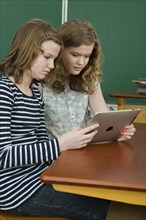 Two schoolgirls in the classroom using a tablet PC