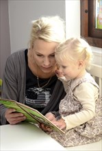 Mother reading a book with her little daughter