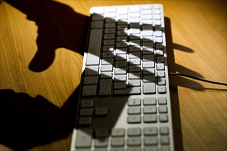 Shadows of two hands on a computer keyboard