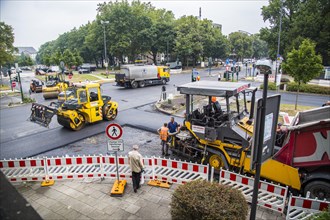Rolling machines and an asphalt spreader during asphalt work on a large urban road construction site