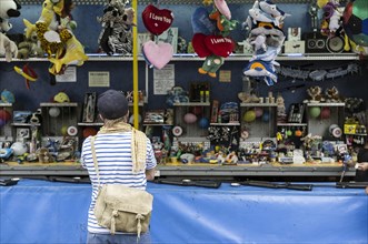 A young man contemplating the shooting gallery at a local fête