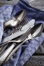 Old tarnished silver cutlery with water drops on a tea towel