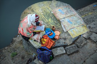 A Hindu devotee reading a holy book along one of the ghats