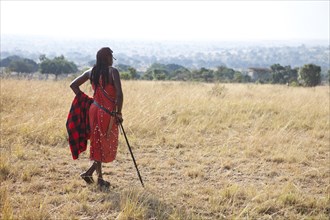 Proud Maasai warrior wearing traditional dress looking out over the savannah