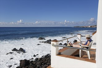 Woman sitting on a balcony by the sea