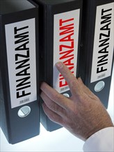Hand reaching for file folders labeled "Finanzamt"