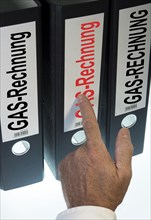 Hand pointing to a ring binder labeled Gasrechnung