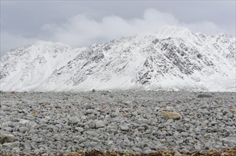 Gravel field in front of a snow-covered summit ridge