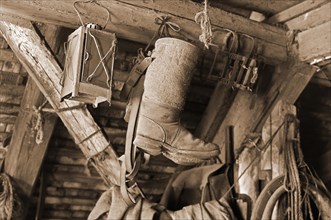 Old stable lantern and felt boots hanging in an attic