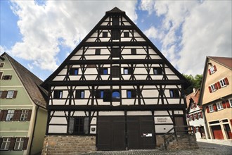 Two-storey half-timbered building on a stone plinth with a steep hipped roof