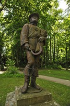 Sculpture of a spelt farmer holding a sickle and a bundle of grain