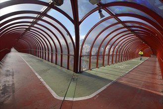 Cyclist is riding on a covered footbridge and bicycle bridge