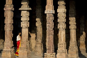 Indian woman walking in between ornately carved stone pillars