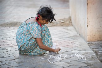 Girl creating a traditional Rangoli