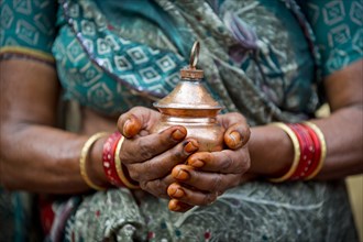 Hands of an Indian woman holding a vessel with holy water