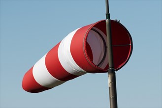 Red and white windsock against a blue sky