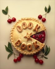 Cherry pie with "Cook Book" written on it in pastry