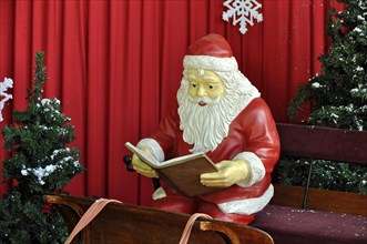 Santa Claus figure sitting on a sled reading