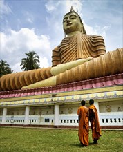 Monks standing in front of giant Buddha statue