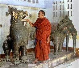 Monk placing his hand into the mouth of a lion statue