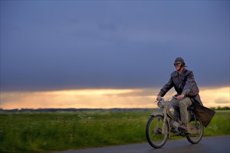 Vintage motorcyclist in front of a dramatic cloudy sky