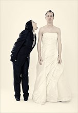 Bride wearing a suit poking her tongue out at the groom wearing a wedding dress