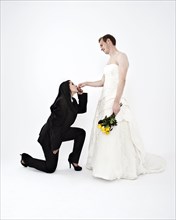 Bride wearing a suit kissing the hand of a groom wearing a wedding dress
