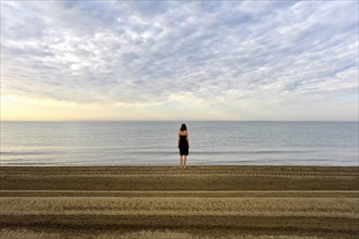 Woman wearing a black dress standing by the sea