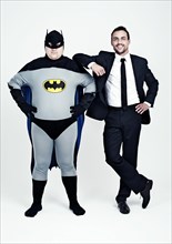 Athletic man wearing a suit beside a fat man dressed as a superhero
