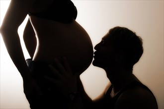 Man kissing the pregnant belly of his wife