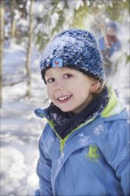 Boy in winter clothes with a snow-covered hat