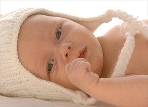 Infant wearing white woollen hat