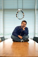 Young man sitting cross-legged on a conference desk