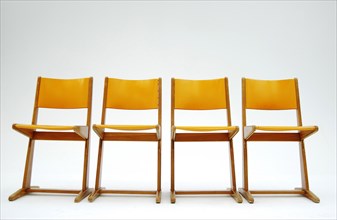 Four old orange school chairs standing side by side