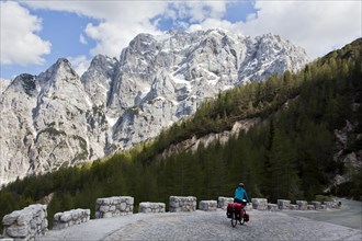 Cyclist in the mountain landscape near the Vrsic Pass with the 2547m high Prisojnik Mountain