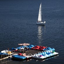 A sailing boat near a pedalo boat hire on Sorpesee Lake or Sorpe Dam