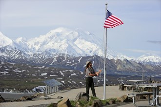 Ranger raises the American Flag in front of Mt McKinley