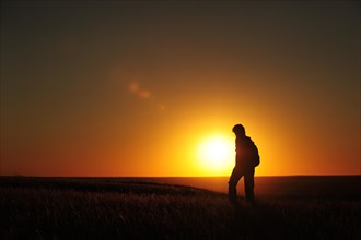 Woman hiking at sunset through the prairie