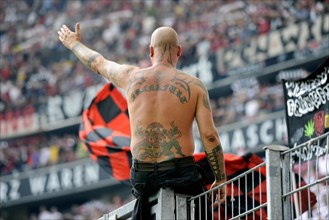 Tattooed Ultra fan of Eintracht Frankfurt sitting on a fence while conducting the crowd