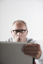 Man looking at a tablet PC with a stunned expression