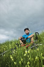 Man sitting with a mountain bike in a meadow