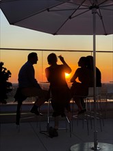 Four persons sundowner on the terrace at sunset