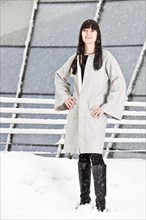 Young woman in a coat standing in the snow