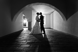 Bride and groom kissing under the arch of an old vault