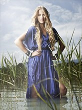 Woman wearing a blue dress standing between the reeds