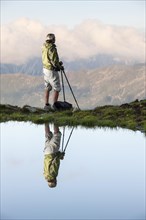 Reflection of a female hiker small lake looking at the Kalkkoegel range