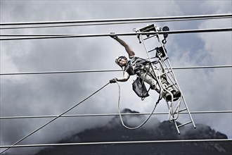 High-voltage service technician pulling a rope to get to the next pylon