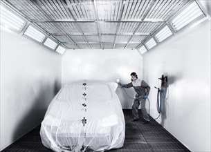 Worker spray-painting a car